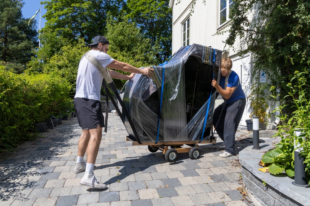 Two Movers Handling a Wrapped Piano